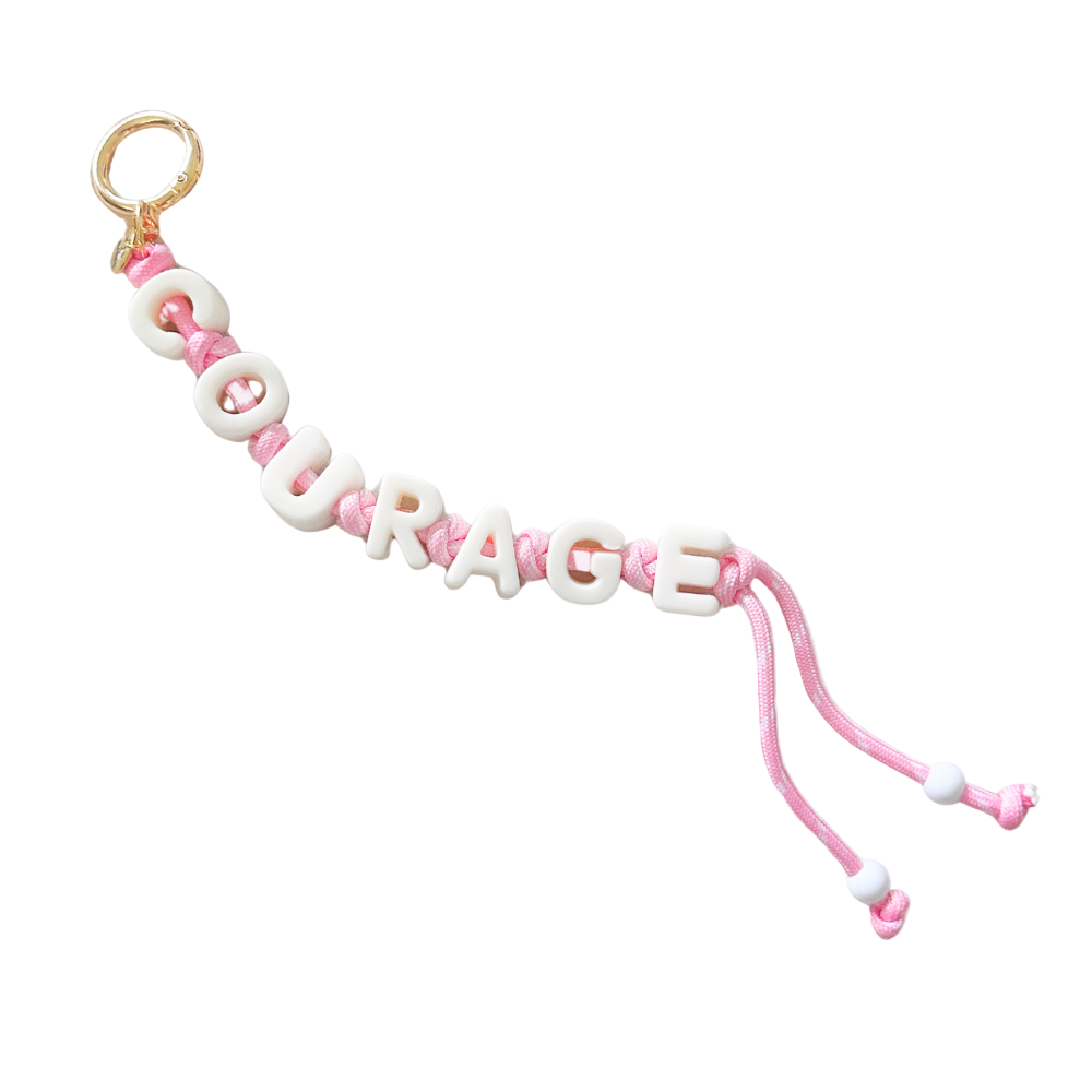 Pink and white 'COURAGE' bracelet on a white background