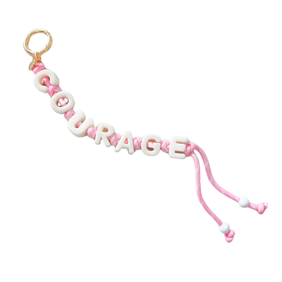 Pink and white 'COURAGE' bracelet on a white background