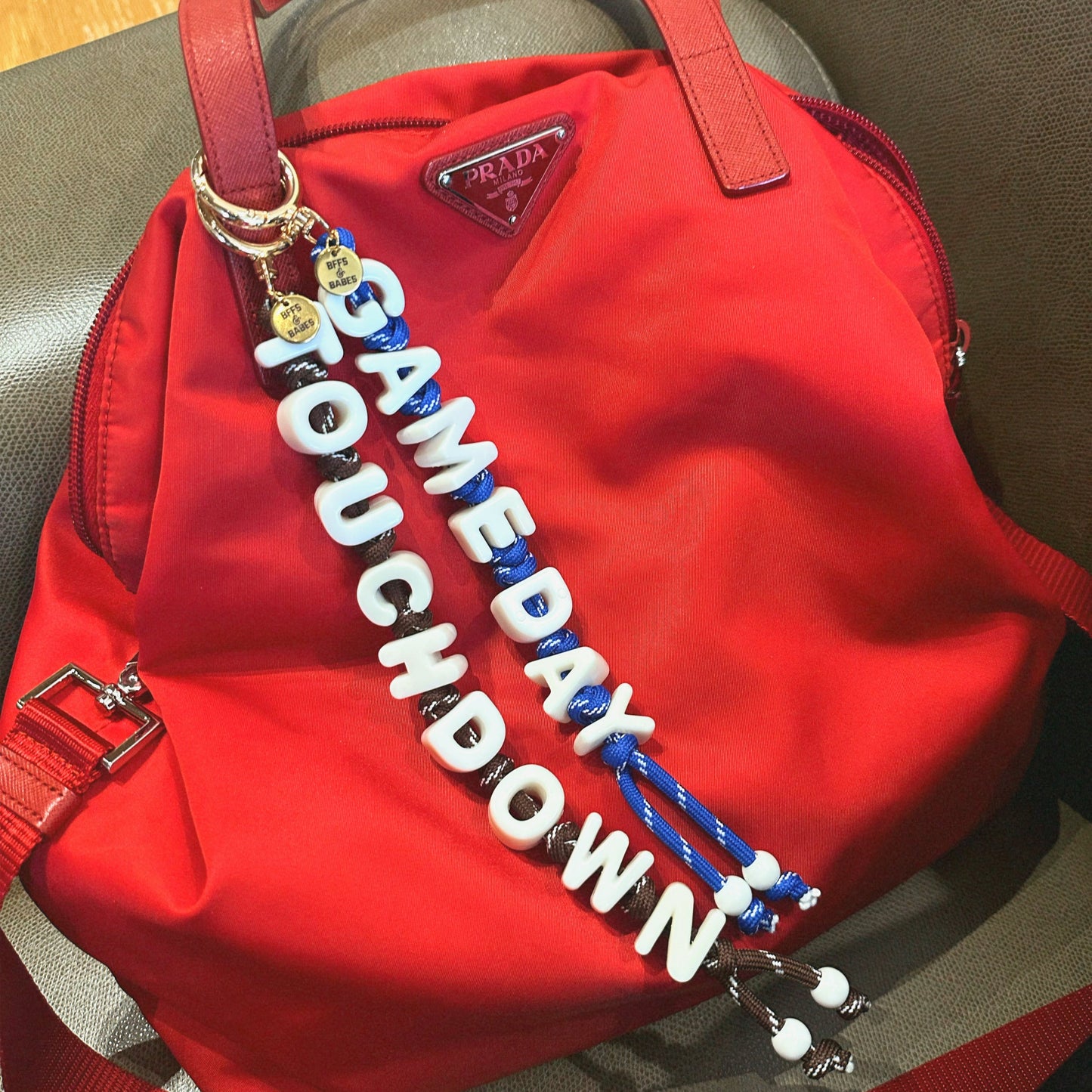 Red bag with a 'GAMEDAY TOUCHDOWN' bag charms on a neutral background